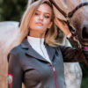 Schöne Frau mit Schimmel Pferd und modernem Turnierjacket in Grau
